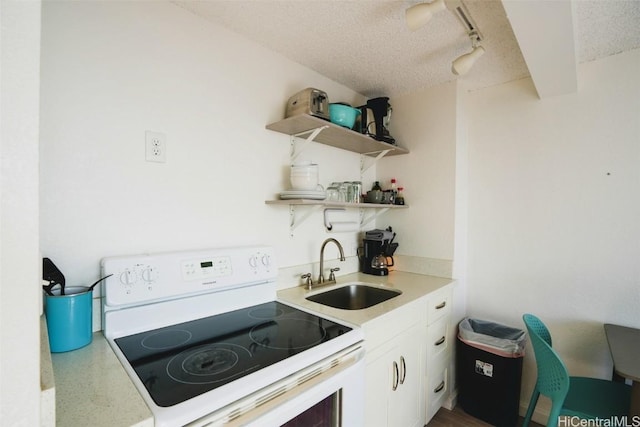 kitchen with white electric range, rail lighting, sink, white cabinets, and a textured ceiling