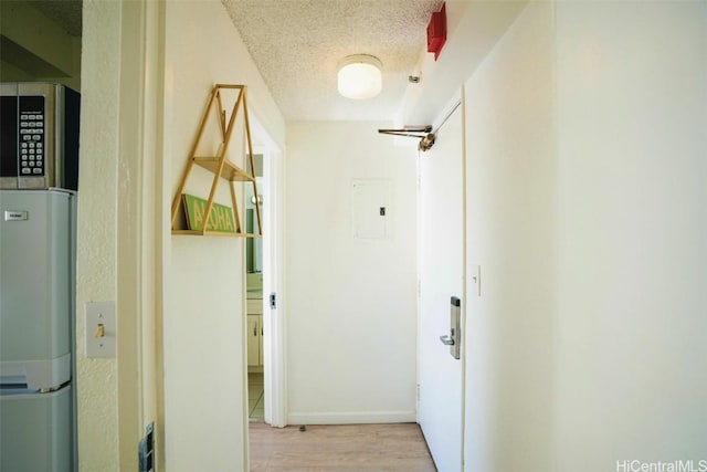 hallway with a textured ceiling and light wood-type flooring