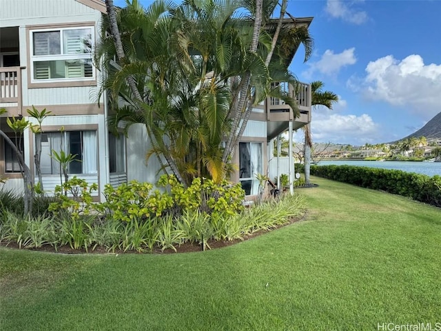 view of home's exterior with a water view and a lawn