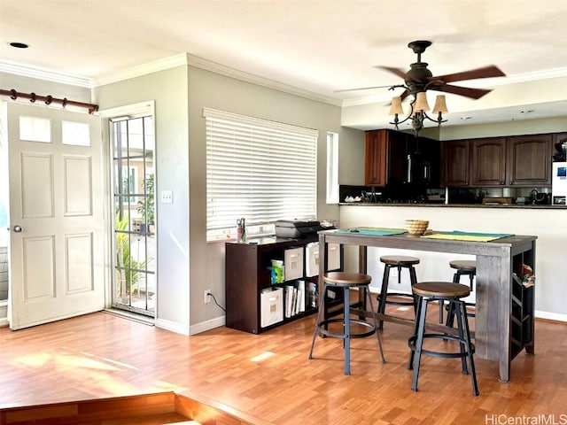 kitchen with ornamental molding, dark brown cabinetry, and a wealth of natural light