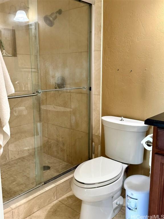 bathroom with an enclosed shower, vanity, tile patterned floors, and toilet