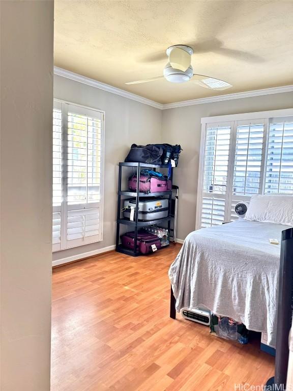 bedroom featuring crown molding, ceiling fan, multiple windows, and hardwood / wood-style flooring