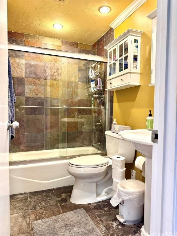 bathroom with crown molding, combined bath / shower with glass door, and toilet