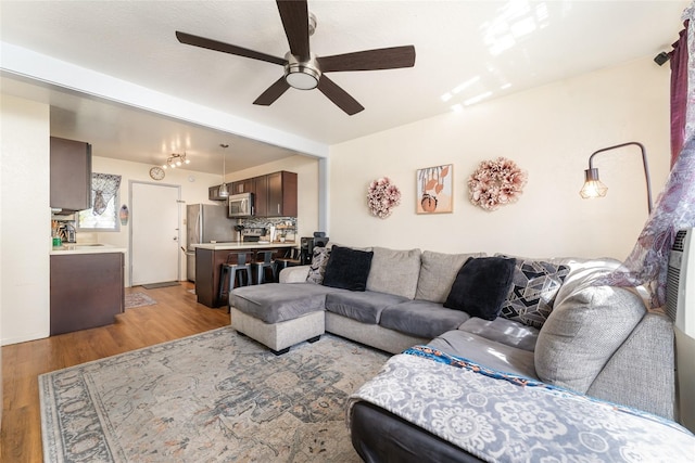 living area with light wood finished floors and a ceiling fan