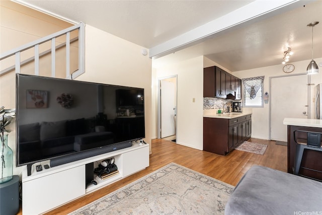 kitchen with a sink, light countertops, light wood-type flooring, and dark brown cabinetry