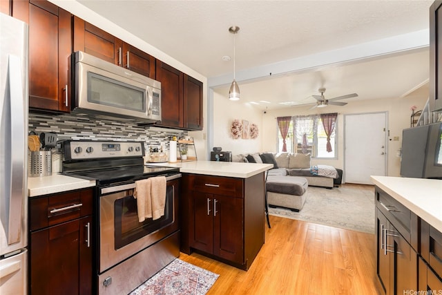 kitchen with light wood-style flooring, a peninsula, appliances with stainless steel finishes, and light countertops