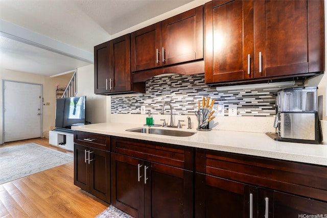 kitchen featuring light countertops, light wood-type flooring, tasteful backsplash, and a sink