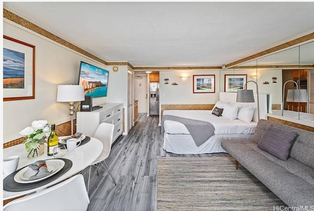 bedroom with dark wood-type flooring and stainless steel fridge with ice dispenser