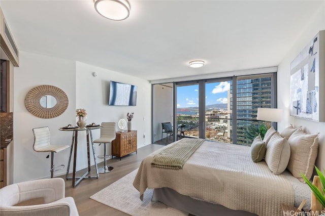 bedroom featuring access to outside, expansive windows, and wood finished floors