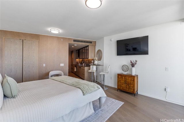 bedroom featuring a sink, light wood finished floors, visible vents, and a closet