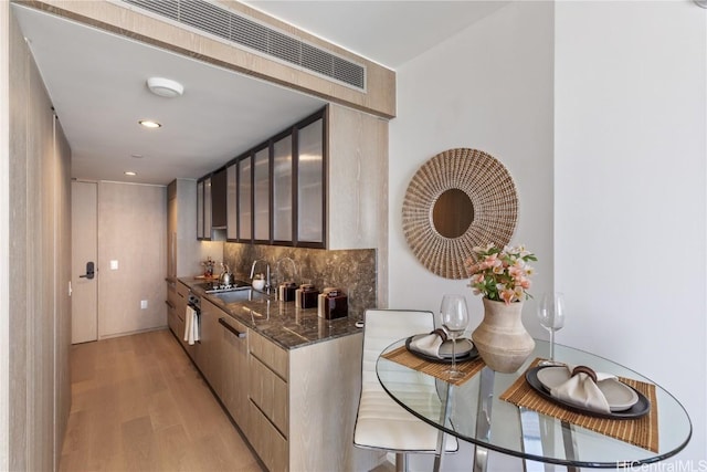 1000 Auahi St Unit 2505, Honolulu, HI 96814 - kitchen with light wood-style flooring, a sink, decorative backsplash, modern cabinets, and glass insert cabinets