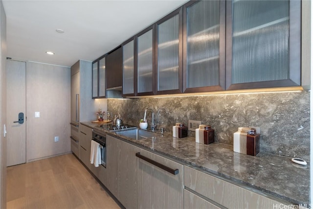 1000 Auahi St Unit 2505, Honolulu, HI 96814 - kitchen with tasteful backsplash, glass insert cabinets, dark stone counters, and a sink
