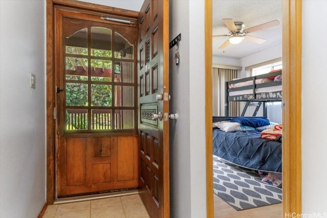 doorway with ceiling fan and light tile patterned floors