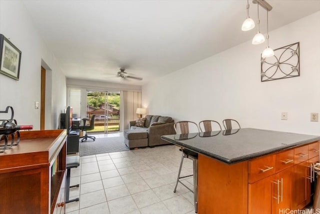 kitchen with a center island, hanging light fixtures, light tile patterned floors, a kitchen breakfast bar, and ceiling fan