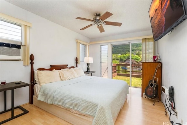 bedroom with multiple windows, cooling unit, access to outside, and light hardwood / wood-style floors