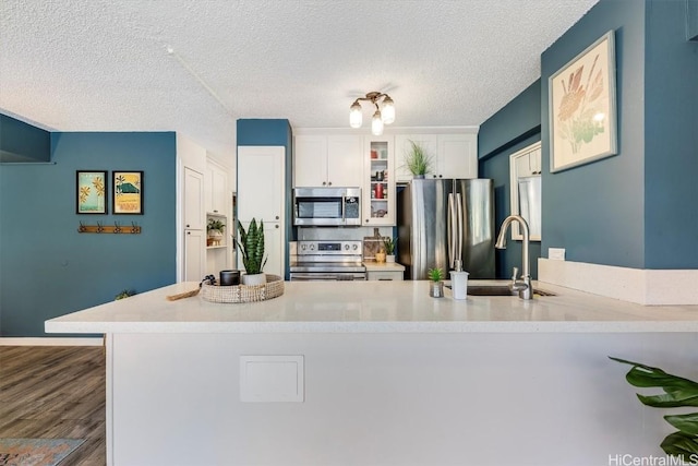 kitchen with stainless steel appliances, light countertops, a sink, and white cabinetry