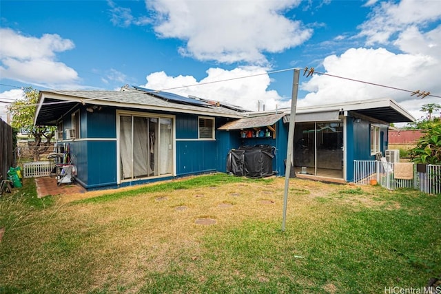 back of property with a lawn and solar panels