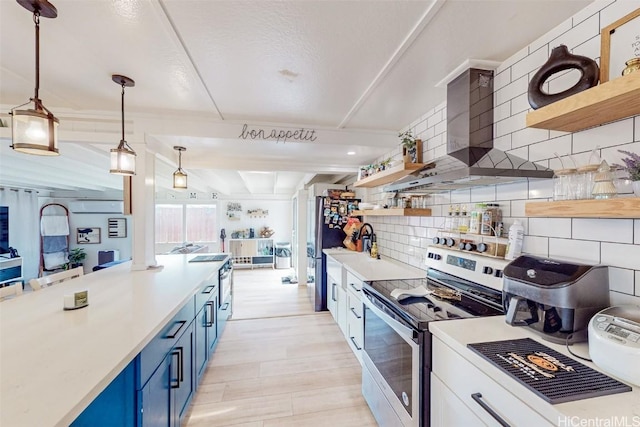 kitchen featuring pendant lighting, wall chimney range hood, blue cabinetry, backsplash, and stainless steel appliances