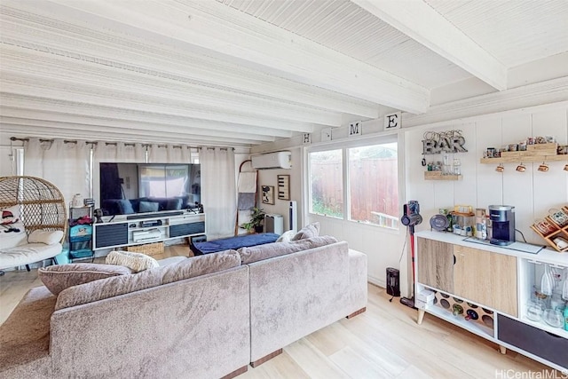 living room with hardwood / wood-style flooring, a wall mounted AC, and beam ceiling