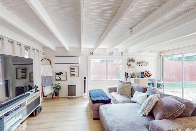 living room featuring beam ceiling, a wall unit AC, and light hardwood / wood-style flooring