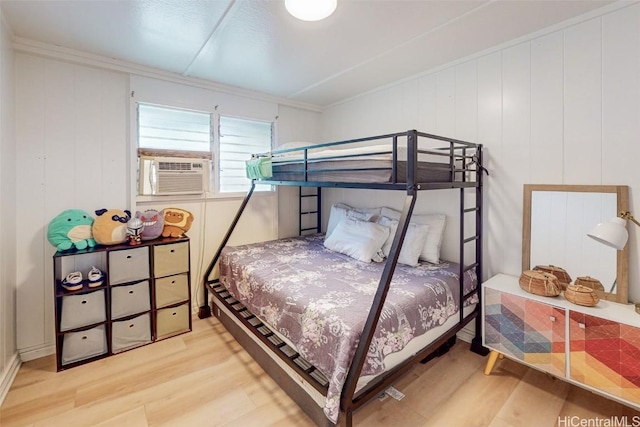 bedroom with cooling unit, light hardwood / wood-style flooring, and ornamental molding