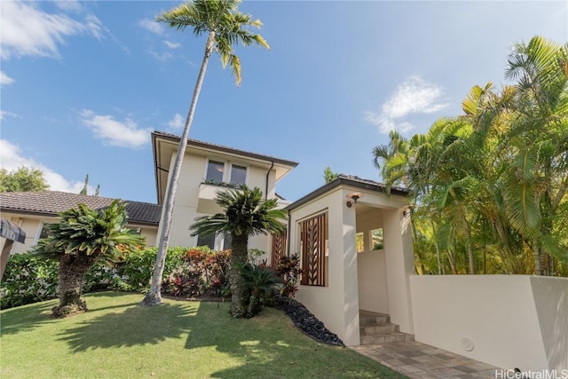 view of front of home featuring stucco siding, a tiled roof, and a front lawn