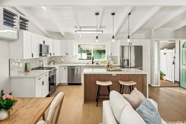 kitchen with pendant lighting, white cabinetry, a center island, and appliances with stainless steel finishes