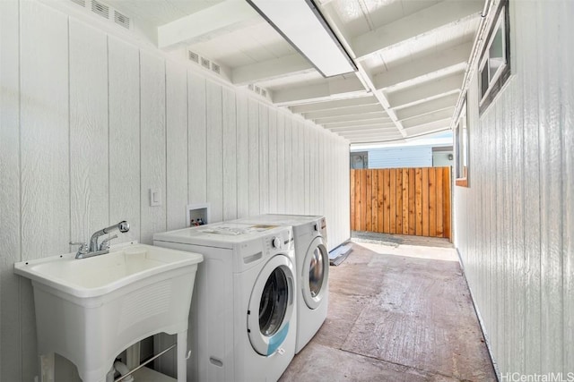 laundry room with separate washer and dryer, sink, and wood walls