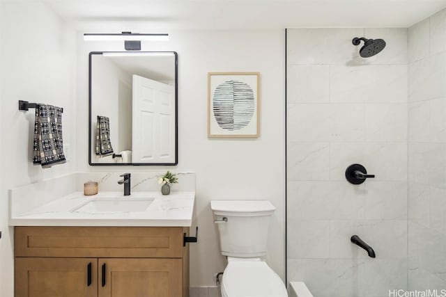 bathroom with tiled shower, vanity, and toilet