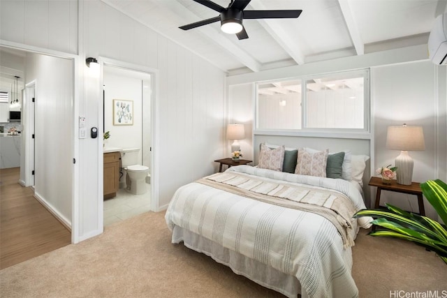 bedroom featuring connected bathroom, a wall mounted AC, light colored carpet, beamed ceiling, and ceiling fan