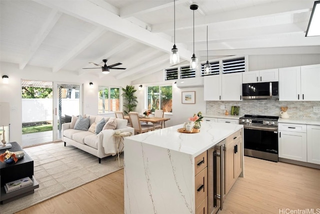 kitchen with stainless steel appliances, a center island, decorative backsplash, and white cabinets