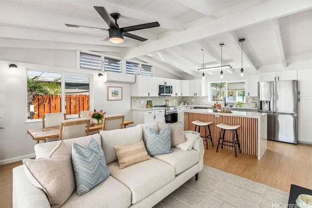 living room with vaulted ceiling with beams, sink, light wood-type flooring, ceiling fan, and a wall unit AC