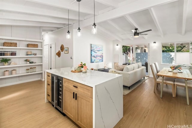 kitchen with pendant lighting, light stone counters, wine cooler, lofted ceiling with beams, and light hardwood / wood-style floors