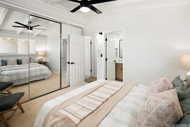 bedroom with beamed ceiling, light carpet, ceiling fan, and a closet