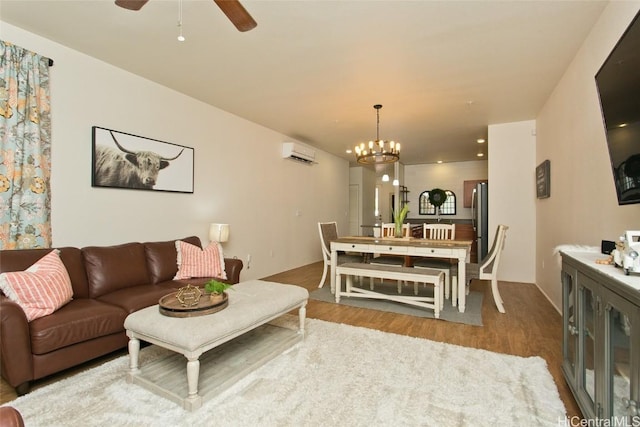 living room featuring wood-type flooring, ceiling fan with notable chandelier, and a wall mounted AC