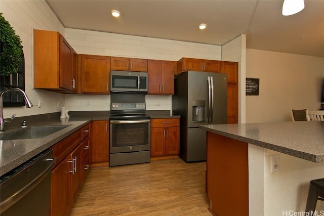 kitchen with appliances with stainless steel finishes, sink, and light wood-type flooring