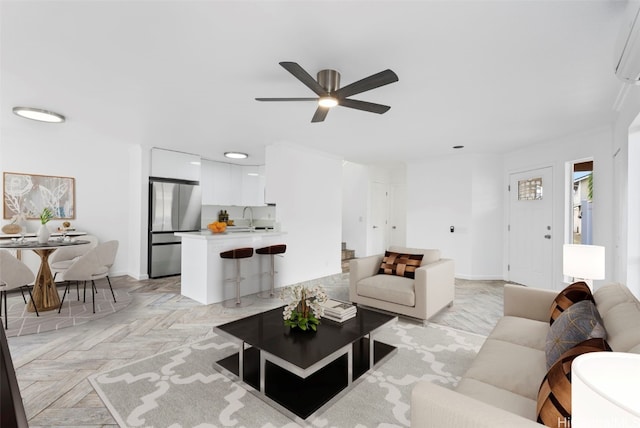 living room with ceiling fan, light parquet flooring, and sink