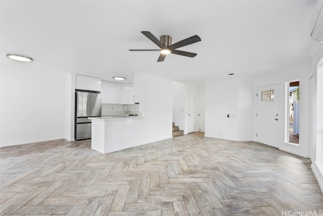 unfurnished living room featuring ceiling fan, light parquet flooring, and sink