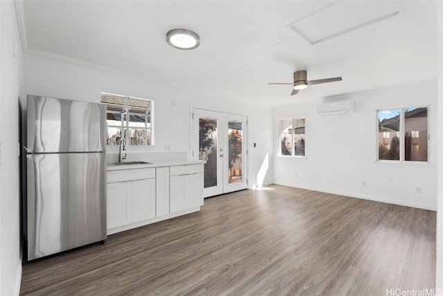 unfurnished living room featuring a healthy amount of sunlight, sink, a wall mounted AC, and dark hardwood / wood-style flooring