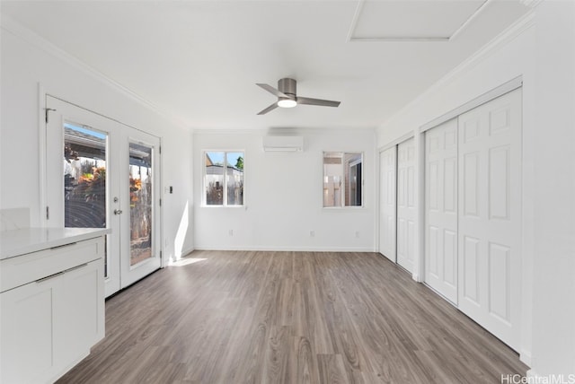 unfurnished living room with crown molding, ceiling fan, wood-type flooring, and a wall mounted AC