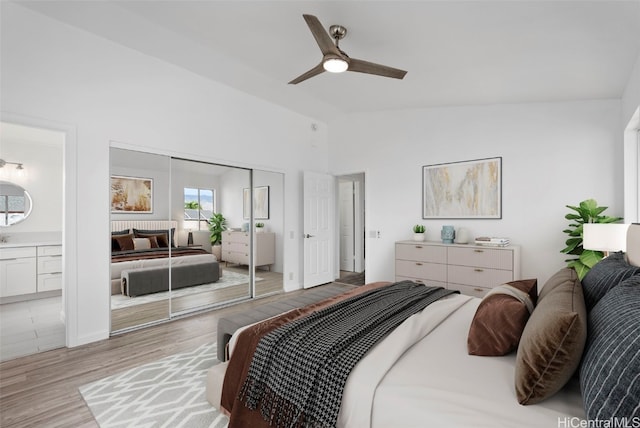 bedroom featuring vaulted ceiling, connected bathroom, ceiling fan, light hardwood / wood-style floors, and a closet