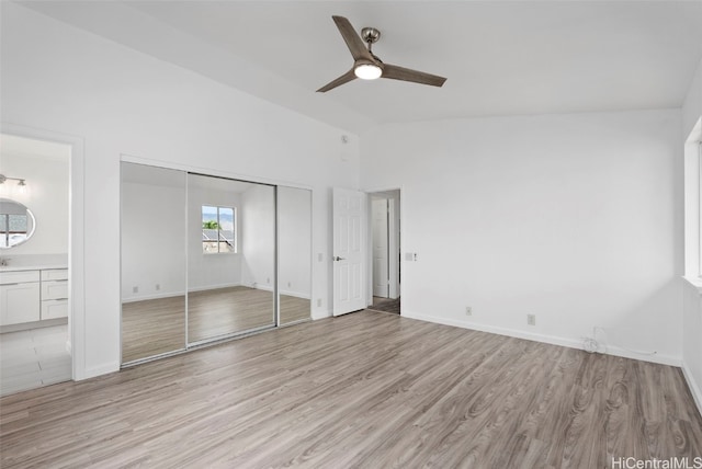 unfurnished bedroom featuring vaulted ceiling, ensuite bath, ceiling fan, and light hardwood / wood-style floors