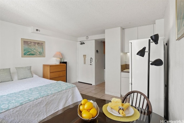 tiled bedroom featuring white refrigerator and a textured ceiling