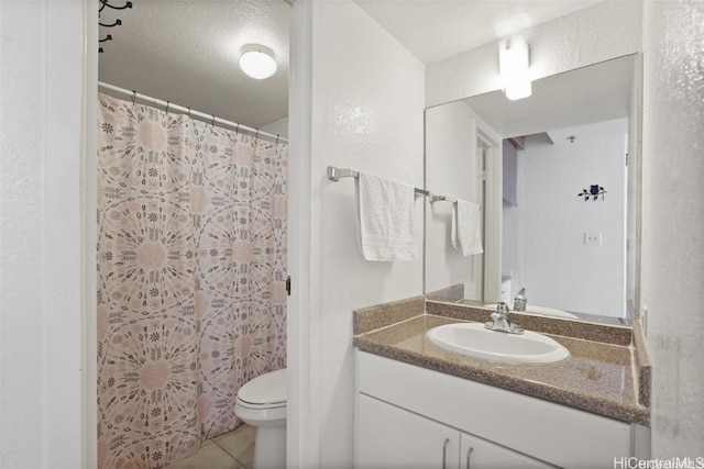 bathroom with tile patterned flooring, vanity, a textured ceiling, and toilet