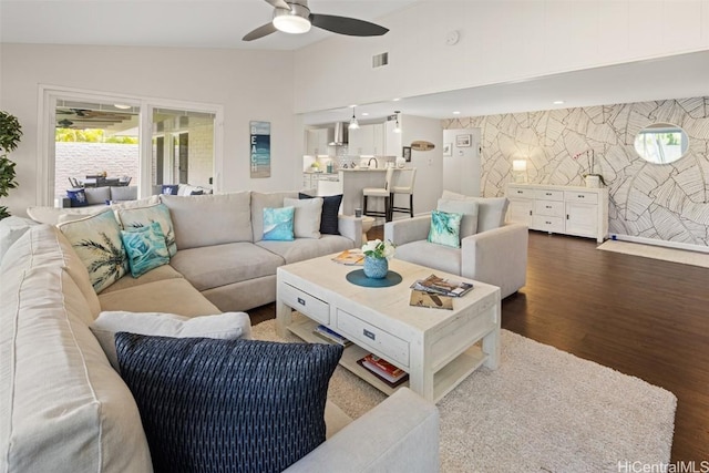 living room featuring dark wood-type flooring, ceiling fan, and vaulted ceiling