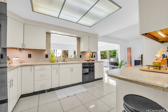 kitchen featuring dishwasher, light tile patterned flooring, white cabinets, and decorative backsplash