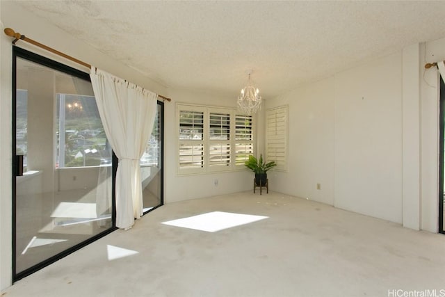 unfurnished room featuring light carpet, a textured ceiling, and a chandelier