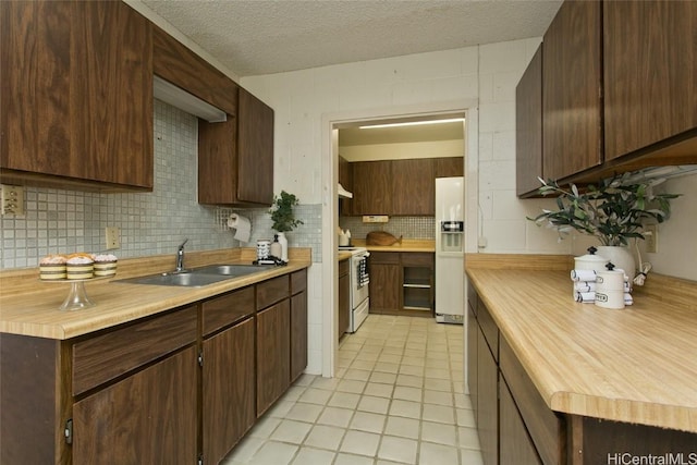 kitchen with sink, white appliances, backsplash, dark brown cabinetry, and a textured ceiling