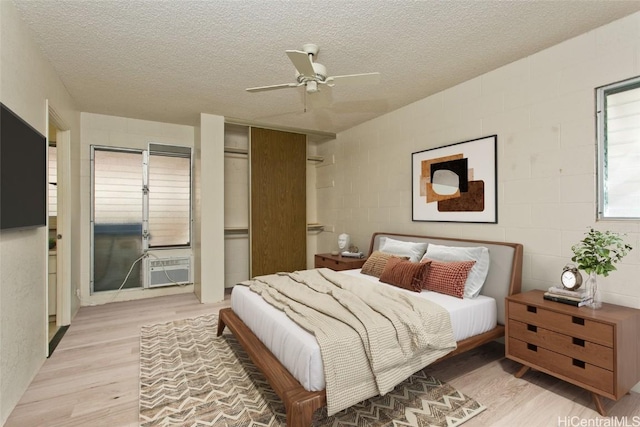 bedroom with a textured ceiling, ceiling fan, and light wood-type flooring