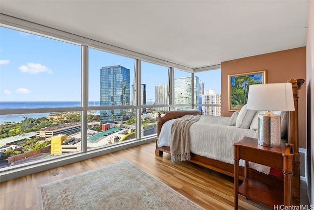 bedroom with hardwood / wood-style flooring, floor to ceiling windows, and a water view